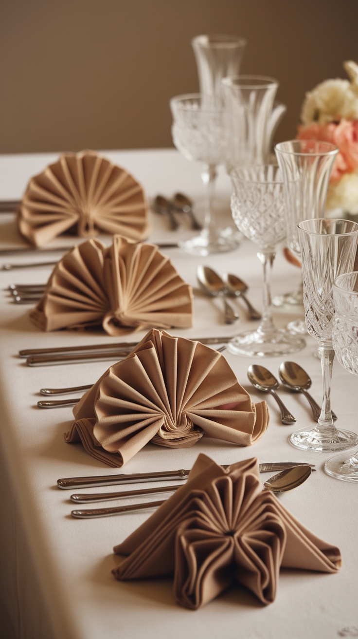 A beautifully set table with creatively folded napkins in fan and bow shapes, surrounded by elegant glassware and cutlery.