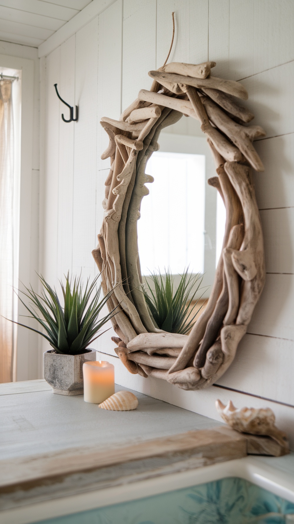 Coastal-themed mirror made of driftwood with plants and seashells in a bathroom setting.